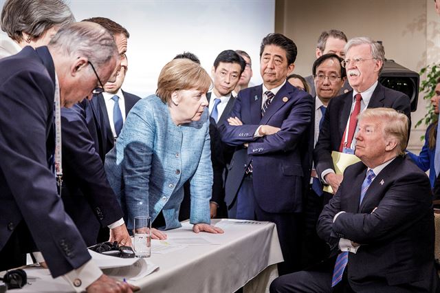 앙겔라 메르켈 독일 총리가 9일(현지시간) 캐나다 퀘벡 주 샤를부아에서 열린 주요 7개국(G7) 정상회의 이틀째 논의에서 팔짱을 끼고 앉은 도널드 트럼프 미국 대통령에게 얘기하고 있다. G7 정상은 회의가 끝난 뒤 보호무역주의와 관세장벽을 배격한다는 공동성명을 발표했지만, 트럼프 대통령이 거부하면서 합의가 무산되는 촌극을 빚었다. 샤를부아 로이터=연합뉴스