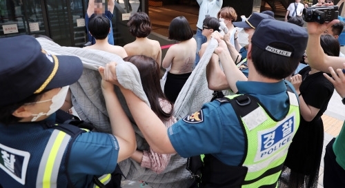 지난 2일 서울 강남구 페이스북코리아 사옥 앞에서 여성단체 회원들이 상의를 벗는 퍼포먼스를 진행하자 경찰들이 서둘러 담요로 이들 주변을 가리고 있다. 뉴스1