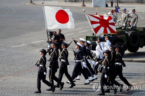 지난 14일 프랑스 파리 샹젤리제 거리를 행진하는 일본 자위대원들. 일장기와 함께 일본 군국주의의 상징물인 욱일 문양이 들어간 자위대기도 들고 나왔다.  [로이터=연합뉴스]