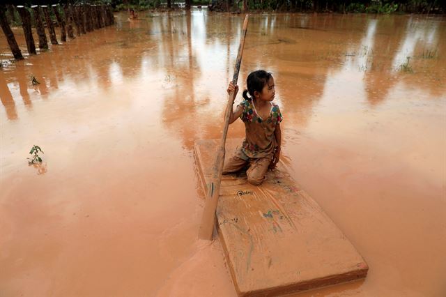 세피안-세남노이 수력발전댐 보조댐이 붕괴돼 홍수 피해를 입은 아타푸주에서 26일 한 소녀가 매트리스를 배처럼 탄 채 이동하고 있다. 아타푸=로이터 연합뉴스
