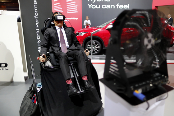 2일 한 관람객이 일본 혼다 전시장에 마련된 버추얼 콕핏 장치에 앉아 운전체험을 하고 있다.[EPA=연합뉴스]