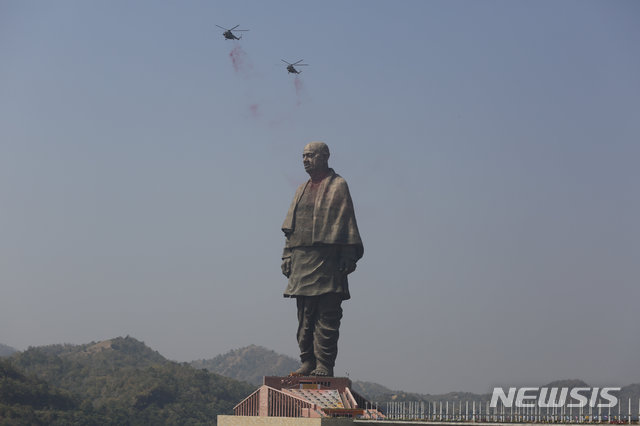 【나라마다(구자라트)=AP/뉴시스】31일 인도 구자라트 주 나라마다에서 세계에서 가장 높은 인도 동상 '통일의 동상' 공개식이 개최돼, 인도 공군이 헬리콥터로 상공에서 꽃가루를 뿌리며 축하하고 있다. 2018.10.31