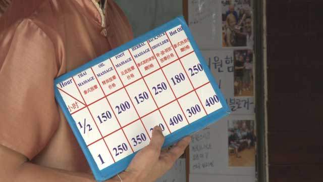 방콕 카오산 로드에서 마사지 가격표를 들고 호객행위를 하는 모습