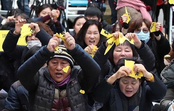 정부가 화해치유재단을 해산한다고 공식 발표한 21일 서울 종로구 옛 일본대사관 앞에서 열린 수요집회에서 시민들이 ‘2015한일합의’, ‘ 화해치유재단’이라고 적힌 종이를 찢고 있다. 연합뉴스