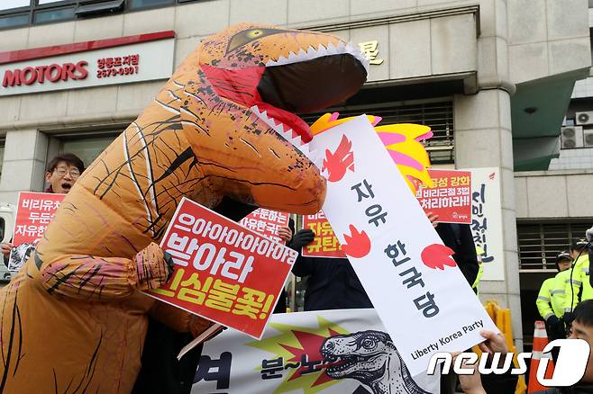 5일 오전 서울 영등포구 자유한국당 당사 앞에서 열린 '유치원 비리근절 3법 통과 촉구 및 자유한국당 규탄 참여연대 기자회견'에서 참가자들이 한국당 현판을 먹는 민심공룡 퍼포먼스를 하고 있다. 2018.12.5/뉴스1 © News1 안은나 기자