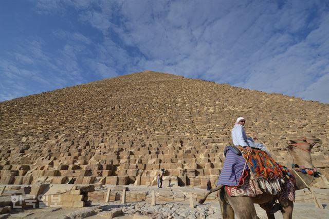 이집트 수도 카이로의 쿠푸피라미드 앞에서 낙타를 탄 상인이 관광객을 찾아 어슬렁거리고 있다.