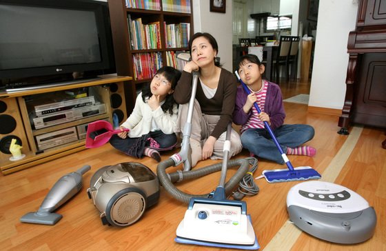 한 가족이 로봇청소기, 스팀청소기, 진공청소기, 빗자루를 들고 골똘히 생각하고 있다. [중앙포토]