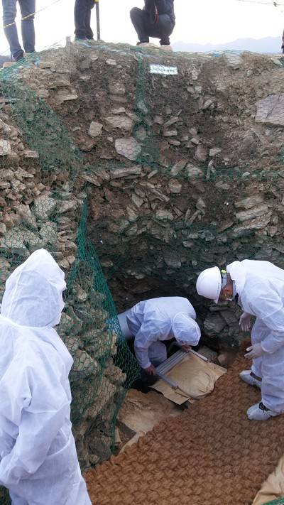 지난 17일 공개된 말이산 13호분 무덤방 입구. 흰 방호복을 입은 조사단원이 사다리를 타고 들어가고 있다.