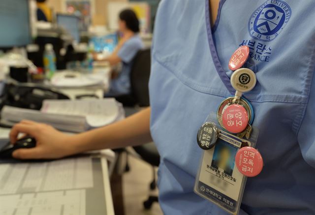 서울 신촌세브란스병원의 한 간호사가 15일 왼쪽 가슴에 분홍색 배지를 여러 개 달고 업무를 보고 있다.