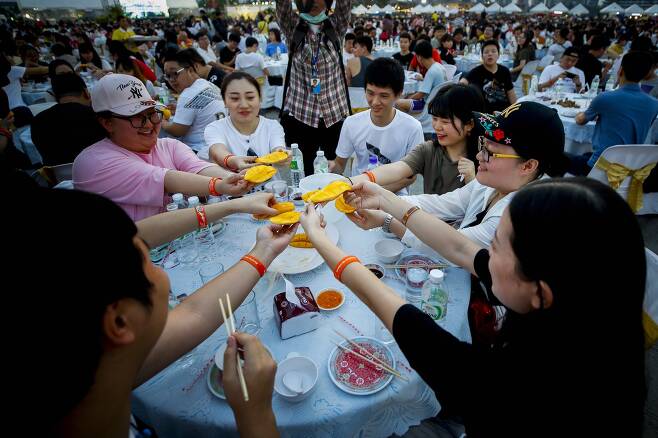 방콕을 방문한 유커들이 20일 망고를 먹고 있다. 만명의 관광객을 위해 4500kg의 망고가 준비됐다. 사상 최대의 망고음식을 즐긴 이날 행사는 기네스북에 기록됐다.[EPA=연합뉴스]