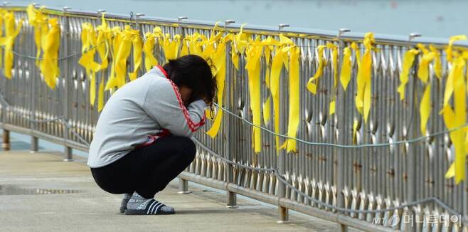 세월호 여객선 침몰 사고 13일째인 2014년 4월28일 오후 전남 진도 팽목항에서 한 여성이 실종자의 무사생환을 기원하는 노란리본 앞에서 기도를 하고 있다./사진=뉴스1