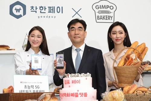 KT 미래플랫폼사업부문장 이동면 사장이 KT 모델들과 16일 서울 광화문 KT스퀘어에서 진행된 KT 블록체인 사업전략 기자간담회에서 블록체인이 적용된 지역화폐 김포페이로 빵을 결제하는 모습을 시연하고 있다. KT.