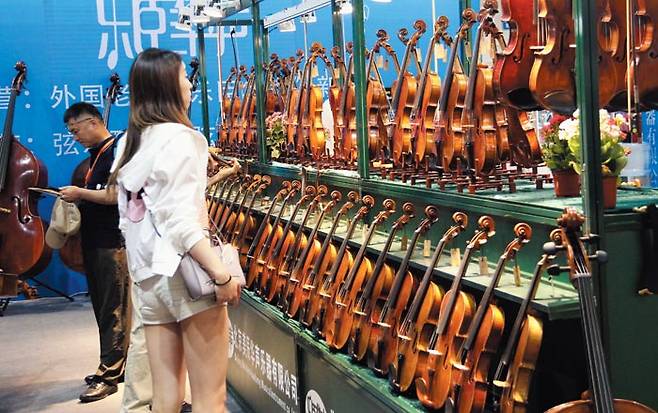 최근 중국 베이징에서 열린 악기 전시회 부스에서 한 참가자가 진열된 바이올린을 바라보고 있다. 중국에서는 지난 수년간 음악 교육 수요가 크게 늘면서 악기 시장 규모도 지난 2017년 기준 448억위안(약 7조7000억원)까지 급성장했다. /베이징=오광진 조선비즈 특파원