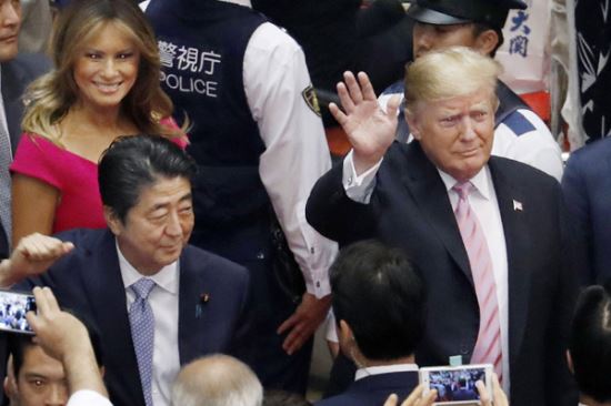 도널드 트럼프 미국 대통령(오른쪽)이 아베 신조 일본 총리와 함께 26일 오후 도쿄의 스모 경기장에 입장하면서 환호하는 관람객들을 향해 손을 흔들고 있다. 그 뒤를 멜라니아 여사가 따르고 있다. 도쿄=AP/뉴시스