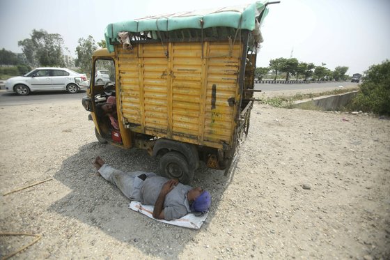 3일 인도 잠무 지역에서 한 인도 근로자가 폭염을 피해 차량 그늘에서 쉬고 있다. [AP=연합뉴스]