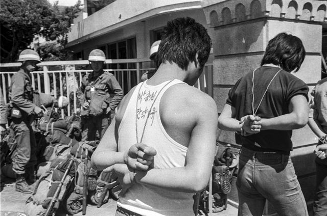 1980년 5월 27일 전남도청에서 체포된 청년들이 계엄군에게 줄줄이 끌려가고 있다. 청년들의 옷에 계엄군이 즉흥적으로 적어놓은 죄목이 보인다. 한국일보 자료사진