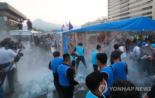 소화기 분말 속 천막 철거 집행 (서울=연합뉴스) 홍해인 기자 = 25일 오전 서울 종로구 광화문 광장에서 농성 중이던 대한애국당(우리공화당) 천막을 서울시와 용역업체 관계자들이 철거 작업에 돌입하자 당원들이 소화기를 뿌려 분말이 광장에 퍼지고 있다. 서울시는 오전 5시 20분부터 천막 2동 등 불법 설치물에 대한 행정대집행을 실시 중이다. 대한애국당은 24일 당명을 '우리공화당'으로 개정했다. 2019.6.25 hihong@yna.co.kr