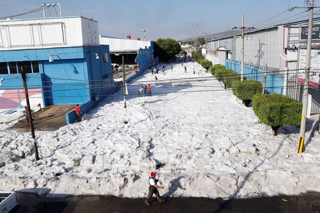 멕시코 과달라하라주 일부 지역에 비와 우박을 동반한 폭풍이 지나간 30일(현지시간) 주민들이 우박이 쌓인 거리를 걷고 있다. EPA 연합뉴스