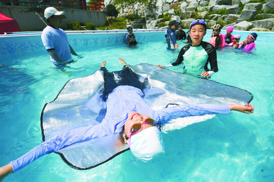 충북 제천 홍광초등학교에서 지난달 5일 열린 ‘이동식 생존수영 교실’에서 학생들이 돗자리를 이용해 물에 뜨는 체험을 하고 있다.