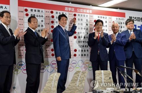 참의원 선거 당선자 이름에 장미 꽃을 붙이는 아베 총리 [AFP=연합뉴스]