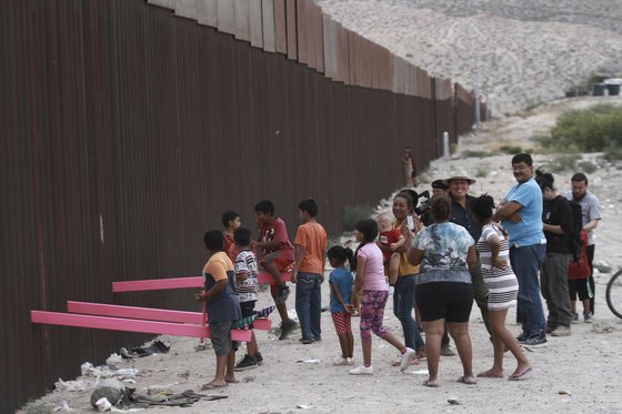 아이들이 멕시코와 미국 국경에 설치된 시소를 타며 놀고 있다. 미국 건축가인 로널드 라엘 캘리포니아대 교수는 28일(현지시간) 미국 텍사스주 엘패소와 멕시코 시우다드후아레스 사이에 화합의 의미를 담은 분홍색 시소를 설치했다. [AP=연합뉴스]