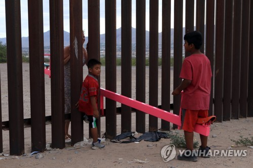 국경 장벽 시소를 타며 소통하는 미국-멕시코 주민들 [AFP=연합뉴스]