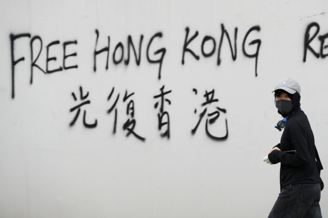 지난 3일 송환법 반대 시위의 상징인 검은색 옷을 입은 한 홍콩인이 ‘자유 홍콩’이라는 글자아래를 지나가고 있다 /AP연합뉴스