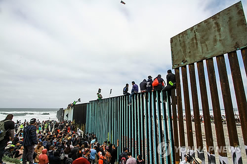 미 국경 지역인 멕시코 티후아나 도착한 '캐러밴' (티후아나<멕시코> EPA=연합뉴스) 중남미 이민자들이 29일(현지시간) 멕시코 국경도시인 티후아나에 도착, 미국과의 국경장벽 앞에 모여 있는 가운데 일부 이민자들은 장벽에 올라 타 있다. 수개월에 걸친 여정 끝에 중남미 출신 이민자 행렬 '캐러밴' 일부가 이날 미 국경 지역인 멕시코 티후아나에 도착했지만, 도널드 트럼프 미국 대통령의 강경한 반 이민 정책으로 이들의 미 입국이 그 어느 때보다 불투명하다. lkm@yna.co.kr