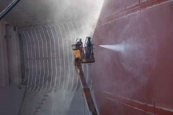 조선소 하청업체 노동자들이 고소차를 타고 도장 작업 전 선박 표면의 염분을 씻어내는 물청소 작업을 하고 있다. 금속노조 제공