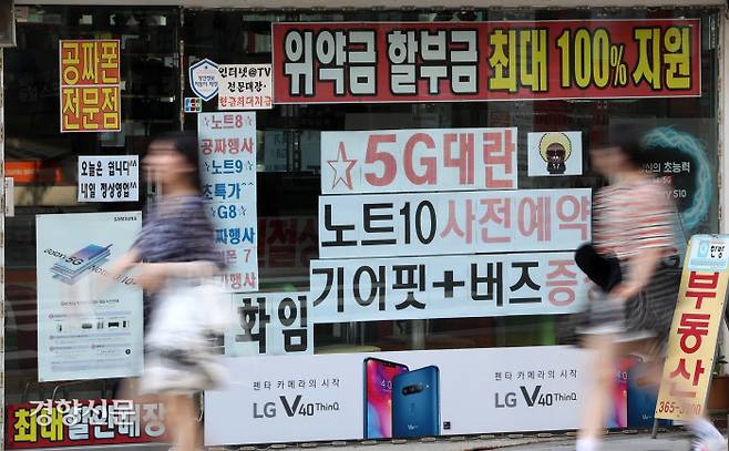 유행이 된 ‘공짜폰 성지’ 좌표 찾기 18일 서울 서대문구에 있는 한 휴대전화 판매점 유리판에 위약금 지원, 공짜폰 전문점 등 소비자들을 끌어들이기 위한 광고 문구가 적혀 있다.  김창길 기자