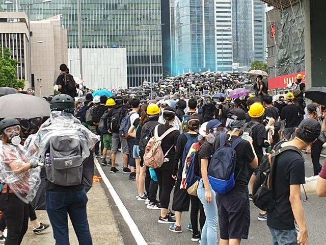 홍콩 시민들이 입법회 앞에서 시위를 벌이는 선봉대를 향해 줄지어 늘어서 헬멧 등 보호장구를 전달하며 힘을 실어주고 있다. 전방에 경찰이 시위대를 향해 쏜 파란색 물대포가 선명하다. 김광수 특파원