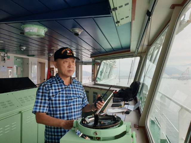 부산항 신항 북컨부두 7번 선석에 입항하는 전장 366미터짜리 선박(M/V OOCL EGYPT·14만1,003톤)에 탑승한 송정규 도선사가 브리지에서 무전기로 예선들과 교신하고 있다./부산=조원진기자
