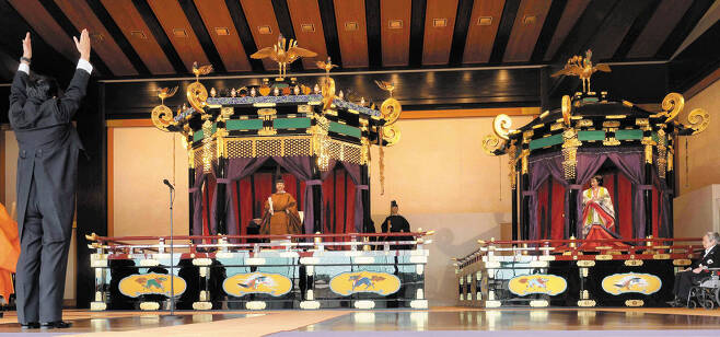 22일 일왕 즉위식이 열린 일본 도쿄 왕궁에서 나루히토(가운데) 일왕과 마사코 왕비 앞에 선 연미복 차림의 아베 신조(왼쪽) 총리가 두 손을 번쩍 들며 만세 삼창을 하고 있다. /AP 연합뉴스