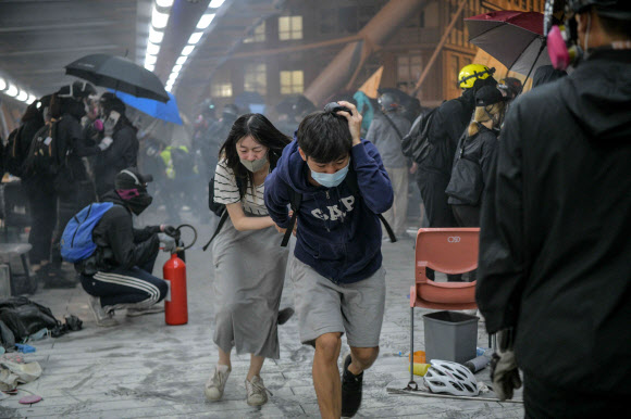 대피하는 학생들 - 18일 홍콩 이공대에서 경찰이 쏜 최루탄을 피해 시위대가 도망치고 있다. 2019.11.19 AFP 연합뉴스