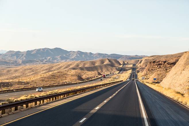 거친 평원 사이에 도로가 실처럼 이어진다