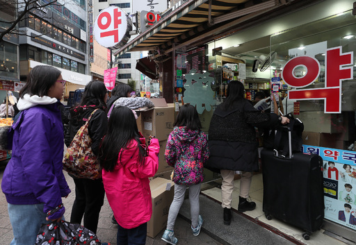 외국인 관광객들이 27일 서울 중구 명동의 한 약국 앞에 마스크를 사기 위해 줄을 서 있다. 연합뉴스