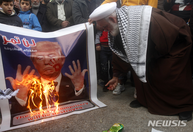 [시돈(레바논)=AP/뉴시스]지난달 29일(현지시간) 레바논 남부 시돈의 한 난민 캠프에서 한 팔레스타인 성직자가 백악관의 '중동평화안'에 반대하는 시위를 벌이며 도널드 트럼프 미국 대통령의 사진을 불태우고 있다. 2020.02.07