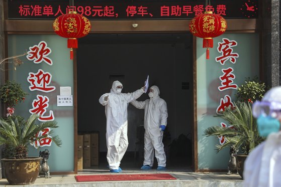 지난 3일 방호복을 입은 남성들이 중국 후베이성 우한시 당국이 격리포인트로 지정한 한 호텔을 나서고 있다. [AP=연합뉴스]