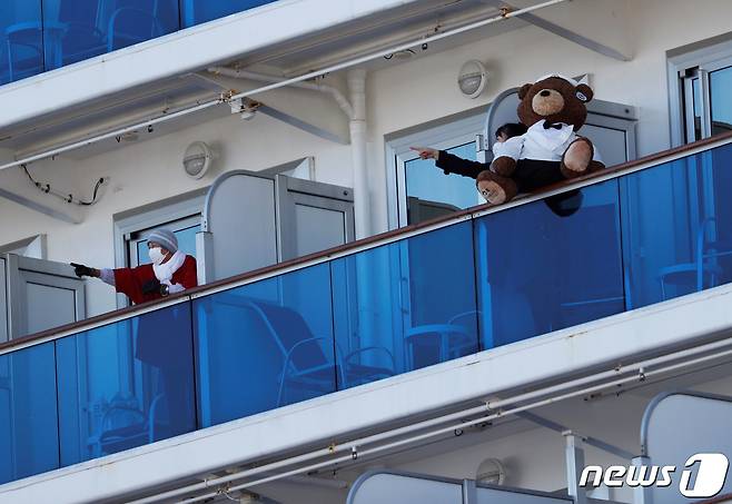일본 요코하마항에 정박 중인 대형 크루즈선 '다아이몬드 프린세스' 승객들이 11일 선실 발코니에 나와 바깥 풍경을 가리키며 대화를 나우고 있다. © 로이터=뉴스1