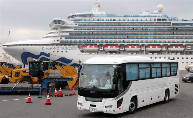 14일 오후 일본 요코하마항에 정박한 대형 크루즈선 다이아몬드 프린세스에서 승객 중 80대 이상 고령자를 대상으로 일부 하선이 시작된 가운데 이들을 실은 버스가 항구를 떠나고 있다. 요코하마=EPA 연합뉴스