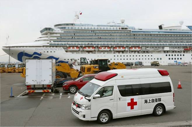 코로나19 환자가 대거 확인된 유람선 '다이아몬드 프린세스'호(뒤쪽)가 정박 중인 일본 요코하마 항에서 구급차 한 대가 출발하고 있다.(사진=연합뉴스)