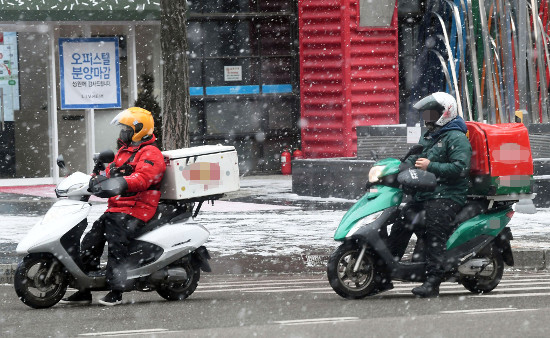 오토바이를 탄 배달원들이 지난 17일 서울 마포구 지하철 2호선 신촌역 인근을 지나고 있다. 많은 눈이 내린 날은 배달 주문이 몰리지만 길이 미끄러워 사고 위험도 높다. 김지훈 기자