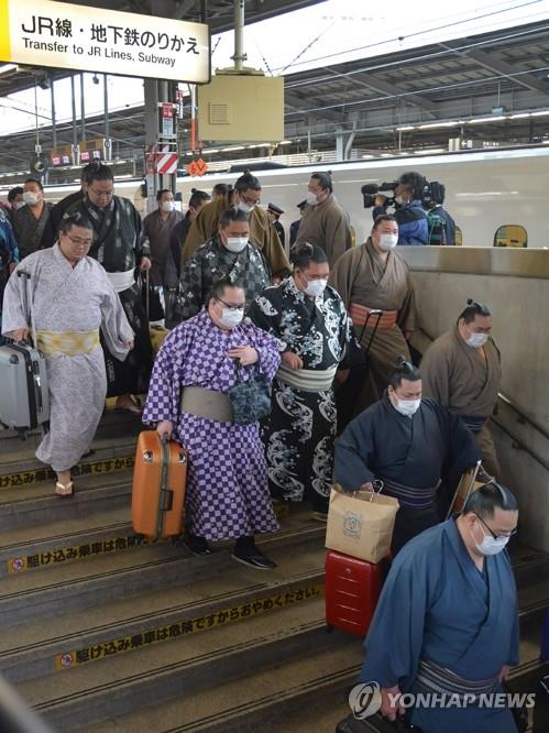 마스크 쓰고 이동하는 일본 스모 선수들 (오사카 AFP=연합뉴스) 일본 스모 선수들이 오사카에서 열리는 3월 대회에 참가하기 위해 23일 마스크를 쓴 모습으로 신오사카역을 빠져나가고 있다. jsmoon@yna.co.kr