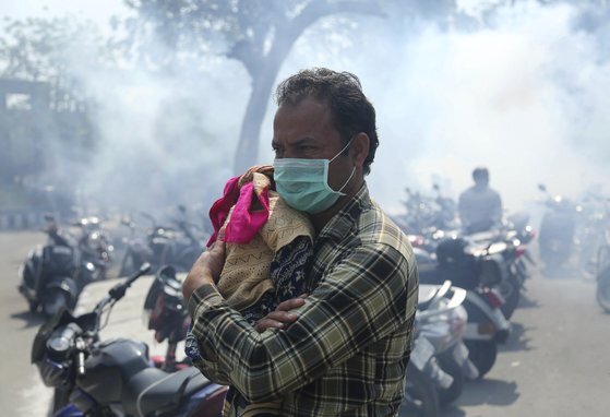 인도에서 마스크를 쓴 한 남성이 아이를 안고 있는 모습. 최근 신종 코로나 확진자가 급증한 인도 정부 역시 발등에 불이 떨어졌다. [AP=연합뉴스]