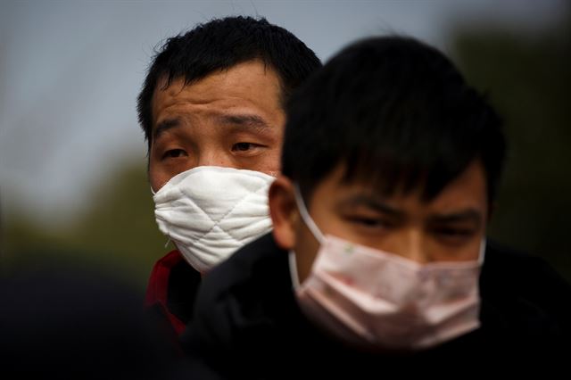 중국 후베이성에서 장시성 지우장으로 넘어가는 검문소 앞에서 두 남성이 마스크를 쓴 채 순서를 기다리고 있다. 지우장=로이터 연합뉴스