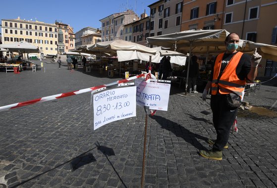 6일 이탈리아 로마에서 영업을 재개한 식료품점 앞에서 마스크를 쓴 직원이 영업 준비를 하고 있다. [신화=연합뉴스]