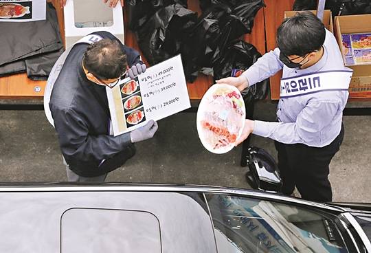 수협중앙회 직원들이 지난달 26일 서울 노량진수산시장에서 차량 운전자에게 포장된 회를 건네주고 있다. 수협은 코로나19 사태로 위축된 수산물 소비를 활성화하기 위해 드라이브스루 판매방식을 도입했다.