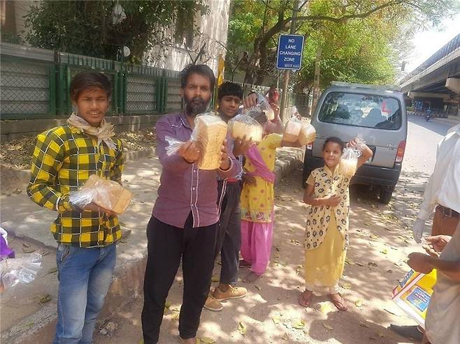뉴델리 교민이 배급한 식빵을 받아 든 인도 빈민들. [뉴델리 교민 제공=연합뉴스]