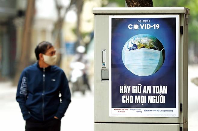 베트남 하노이에 설치된 코로나19 위험을 알리는 표지판 옆을 한 시민이 걷고 있다. ⓒEPA 연합