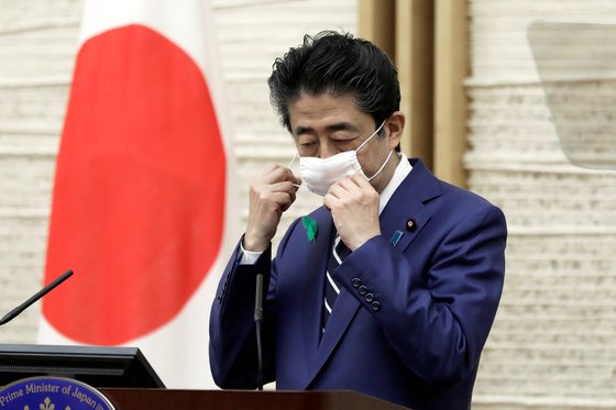 지난 17일 오후 총리관저에서 열린 기자회견을 시작하기 직전 아베 신조 일본 총리가 마스크를 벗고 있다. [로이터=연합뉴스]